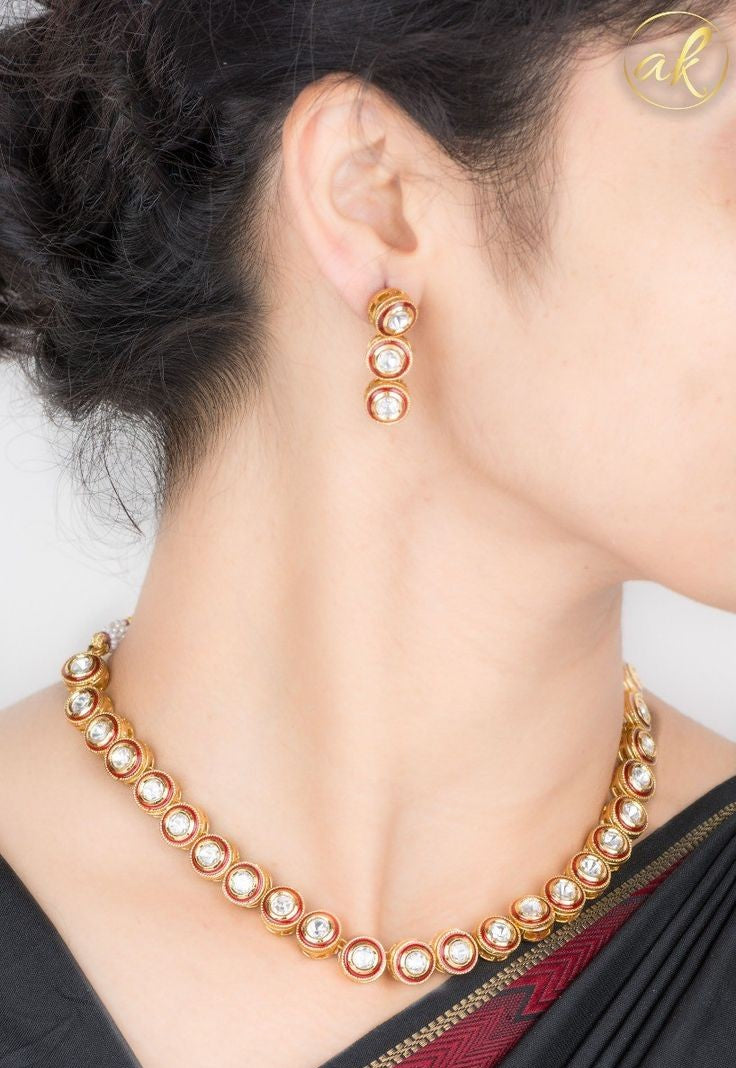 Gold necklace and earrings on a person wearing a black saree with a white blouse.